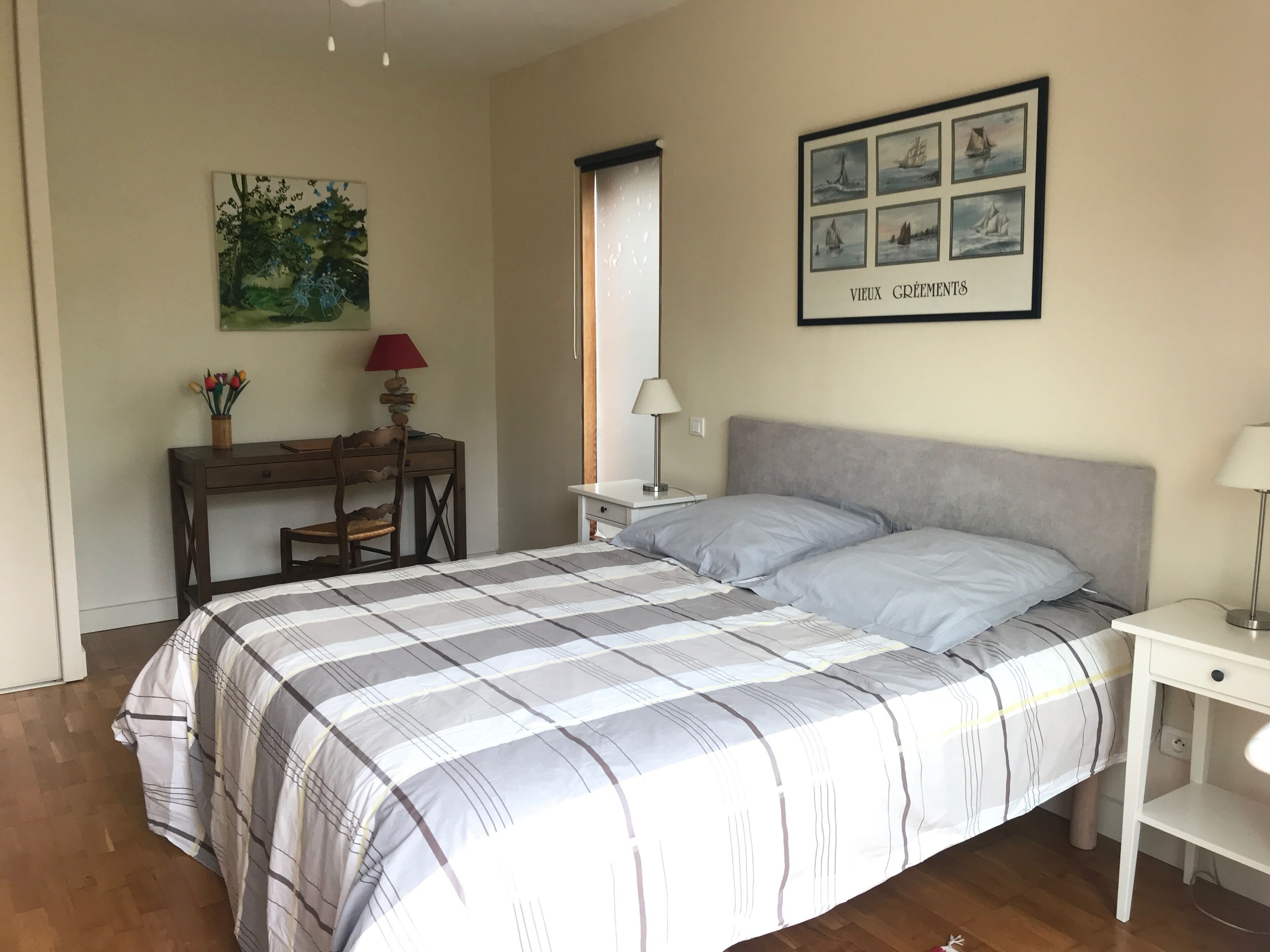 A bedroom with a bed, a desk, a chair, a lamp, and a framed picture on the wall.