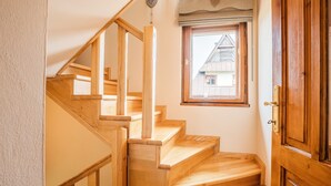 Una escalera de madera con un ventanal arriba.
