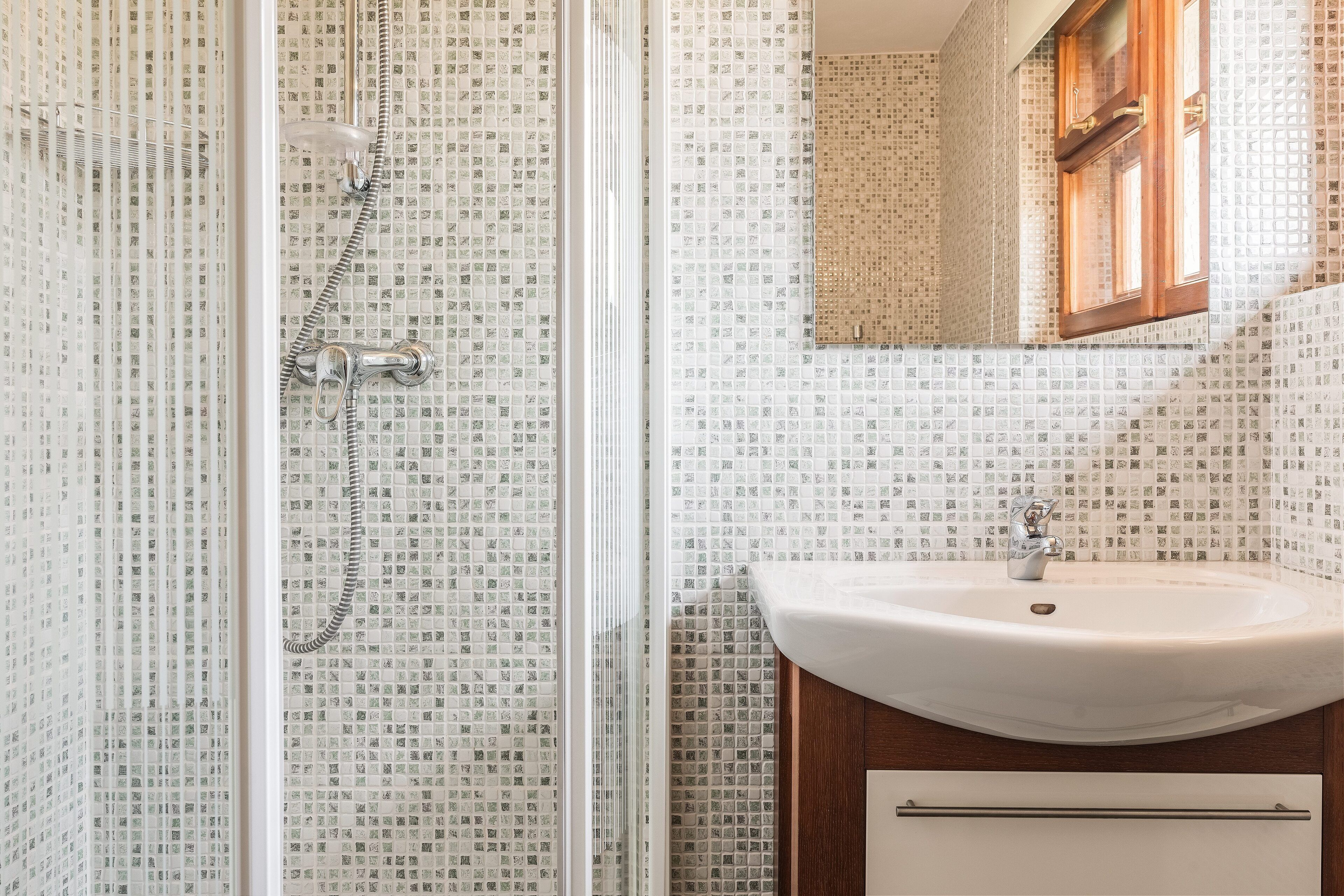 Une salle de bain avec une douche, un lavabo et un miroir.