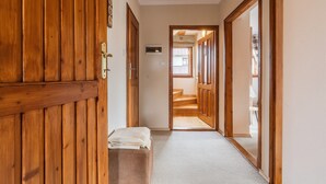 Un pasillo con puertas de madera, un banco y suelo alfombrado.