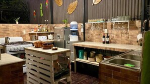 A kitchen with a brick backsplash, wooden cabinets, and a countertop with various kitchen items. - Nueva Villa Paraiso (Lagunillas)