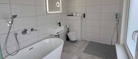 A modern bathroom with a freestanding bathtub, a toilet, and a shower area.