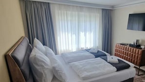 Una cama doble con sábanas blancas, un cabecero de madera y una mesita de noche con una lámpara.