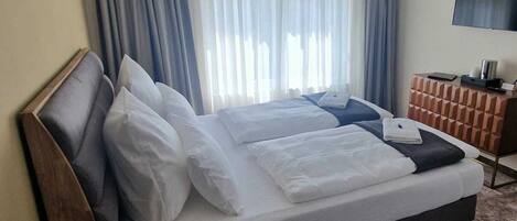 Een tweepersoonsbed met witte lakens, een houten hoofdbord en een nachtkastje met een lamp.