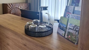 Una habitaci ón de hotel con una mesa de comedor de madera, una cafetera de vidrio y una bandeja con azúcar y leche condensada.