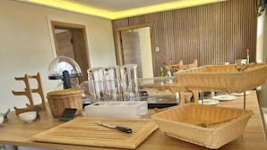 Una cocina moderna con encimera de madera, utensilios de cocina y un comedor con una silla de mimbre.