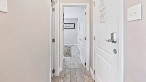 Un pasillo estrecho con puertas blancas, una alfombra en el suelo y un cartel en una puerta.