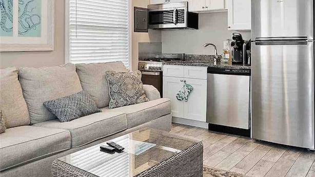 Cocina compacta con armarios blancos, un refrigerador de acero inoxidable y un microondas.