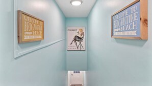 Un pasillo con paredes azul claro, tres carteles enmarcados en la pared y una puerta blanca al final.