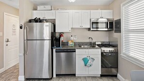 Cocina compacta con refrigerador, microondas, estufa y lavavajillas.
