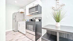Una cocina moderna con electrodomésticos de acero inoxidable, armarios blancos y piso de madera.