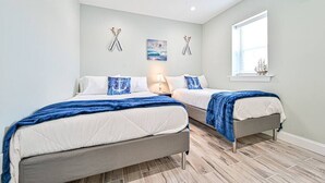Un dormitorio con dos camas, una ventana y decoración náutica.