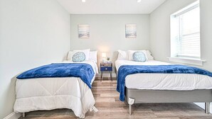 Een slaapkamer met twee bedden, een nachtkastje en een raam.