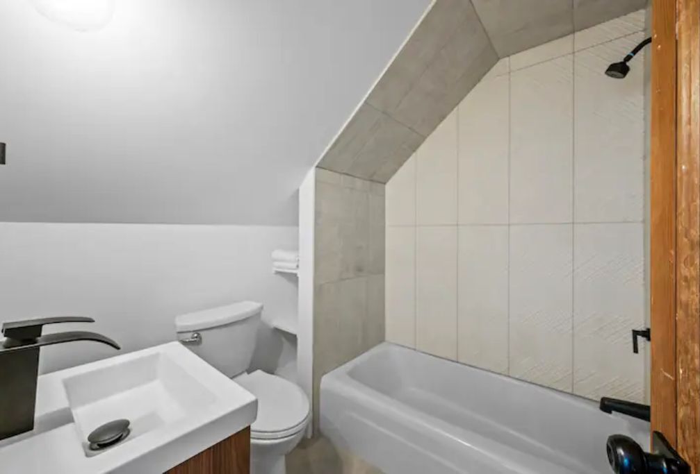 Un baño moderno con lavamanos, inodoro y bañera blancos.