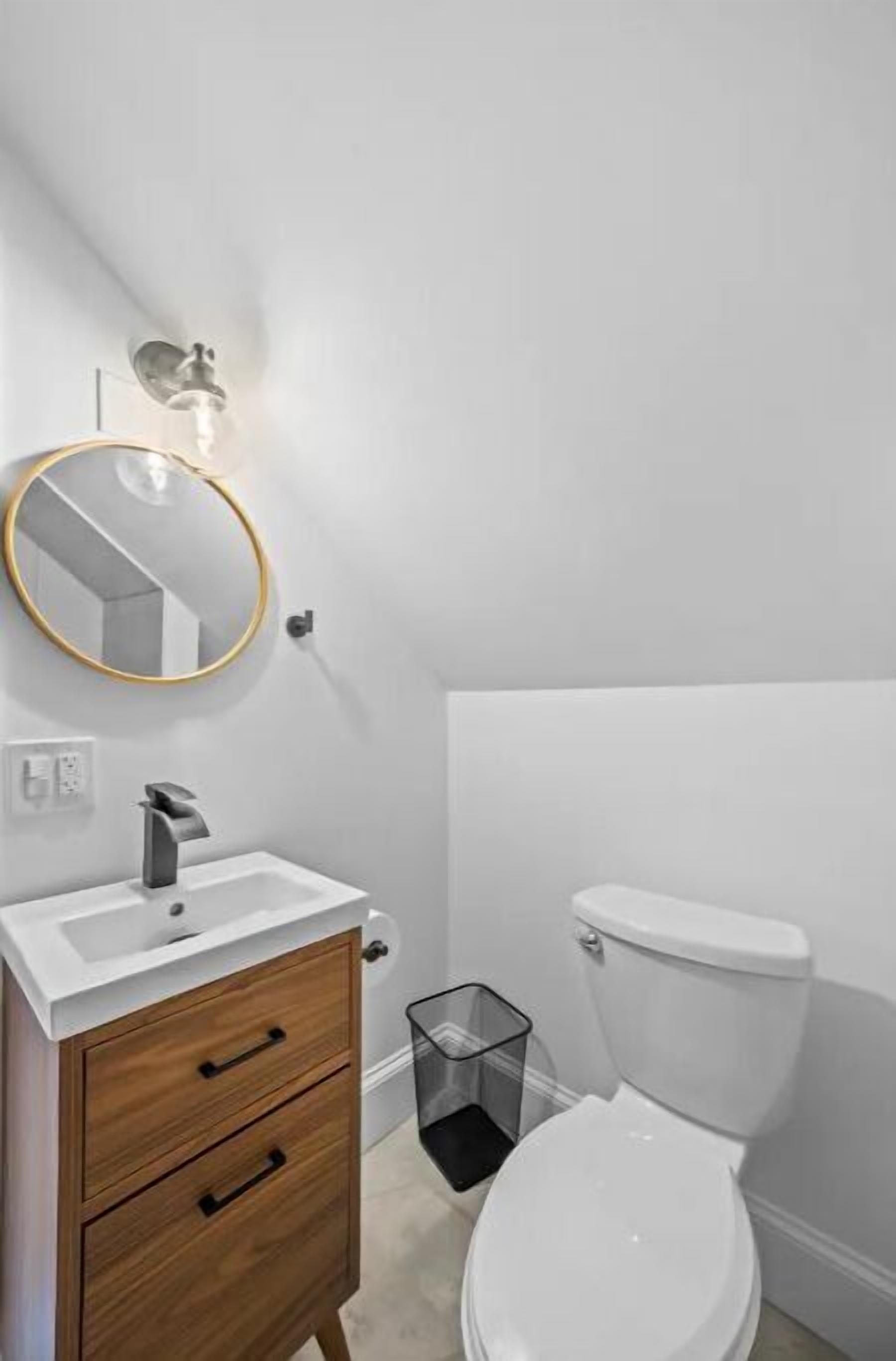 Een moderne badkamer met een witte wastafel, een houten kastje en een toilet.