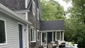 A covered deck with outdoor furniture, a grill, and a view of the house. - Four Winds Cottage (Southwest Harbor)