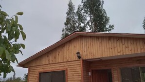 A wooden cabin with a large window and a door, surrounded by trees. - Eco Yoga Lounge Illawara (Illapel)