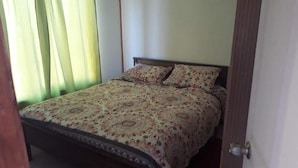A bedroom with a bed, curtains, and a door. - Eco Yoga Lounge Illawara (Illapel)