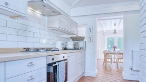 Eine moderne Küche mit weißen Schränken, einer zentralen Kochinsel und einem Essbereich mit Tisch und Stühlen.