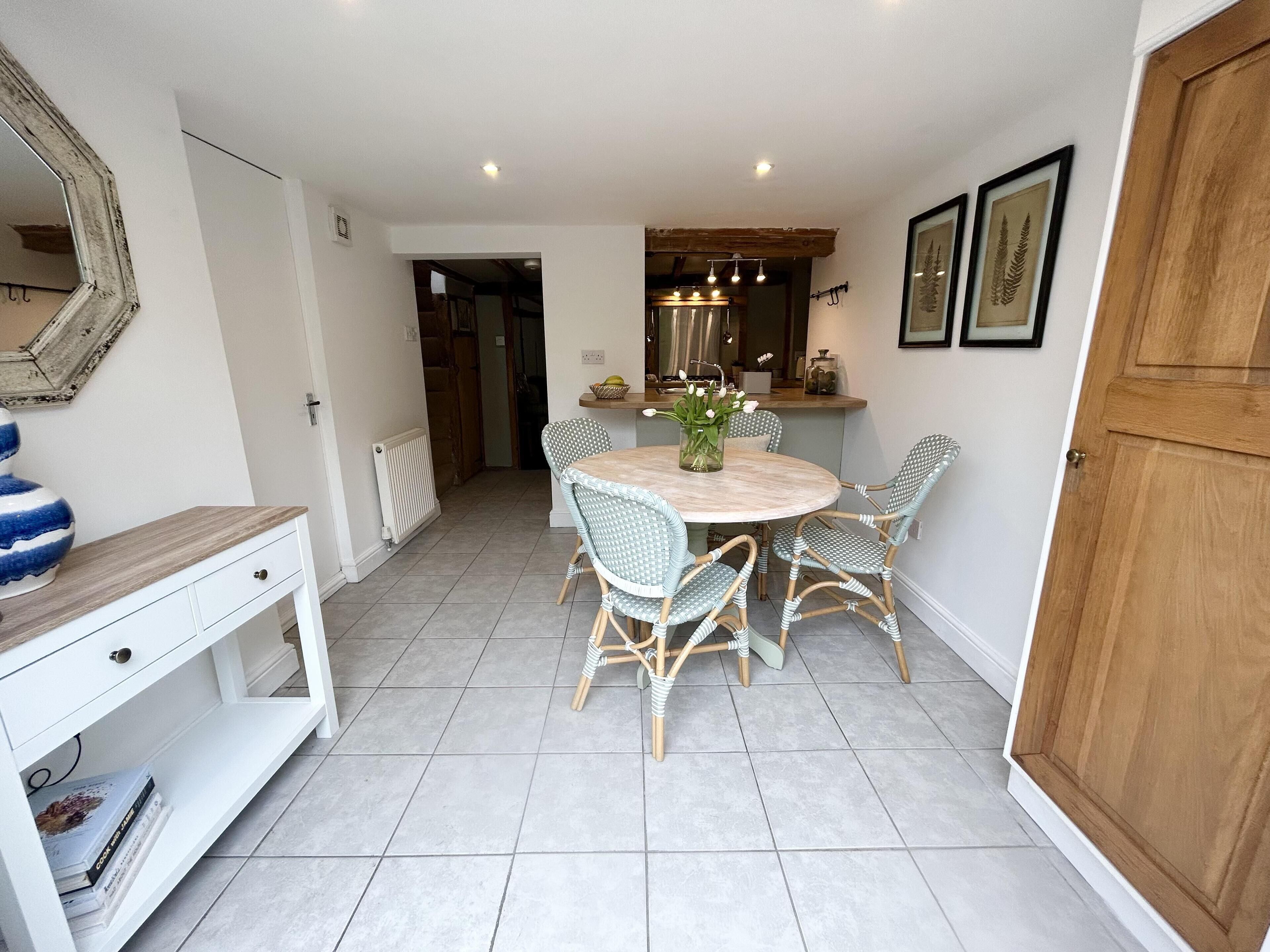 A dining area with a round table, wicker chairs, and a white cabinet.