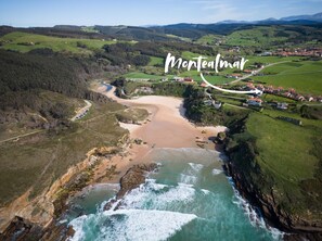 An aerial view of Montealmor, featuring a coastal landscape with a beach, rocky shoreline, and surrounding green fields. - Montealmar Galizano Somo (ribamontan al mar)
