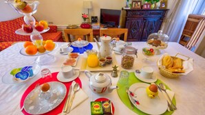Una mesa de desayuno servida con diversos platos, entre ellos frutas, pasteles y bebidas.