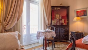 Una habitación de hotel con una cama, una mesa con mantel de encaje, un armario de madera y un cuadro en la pared.