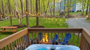 A hot tub on a wooden deck with a fire in the background. - Private Wooded Escape + Hot Tub + Fire Pit and Screen Porch (East Stroudsburg)