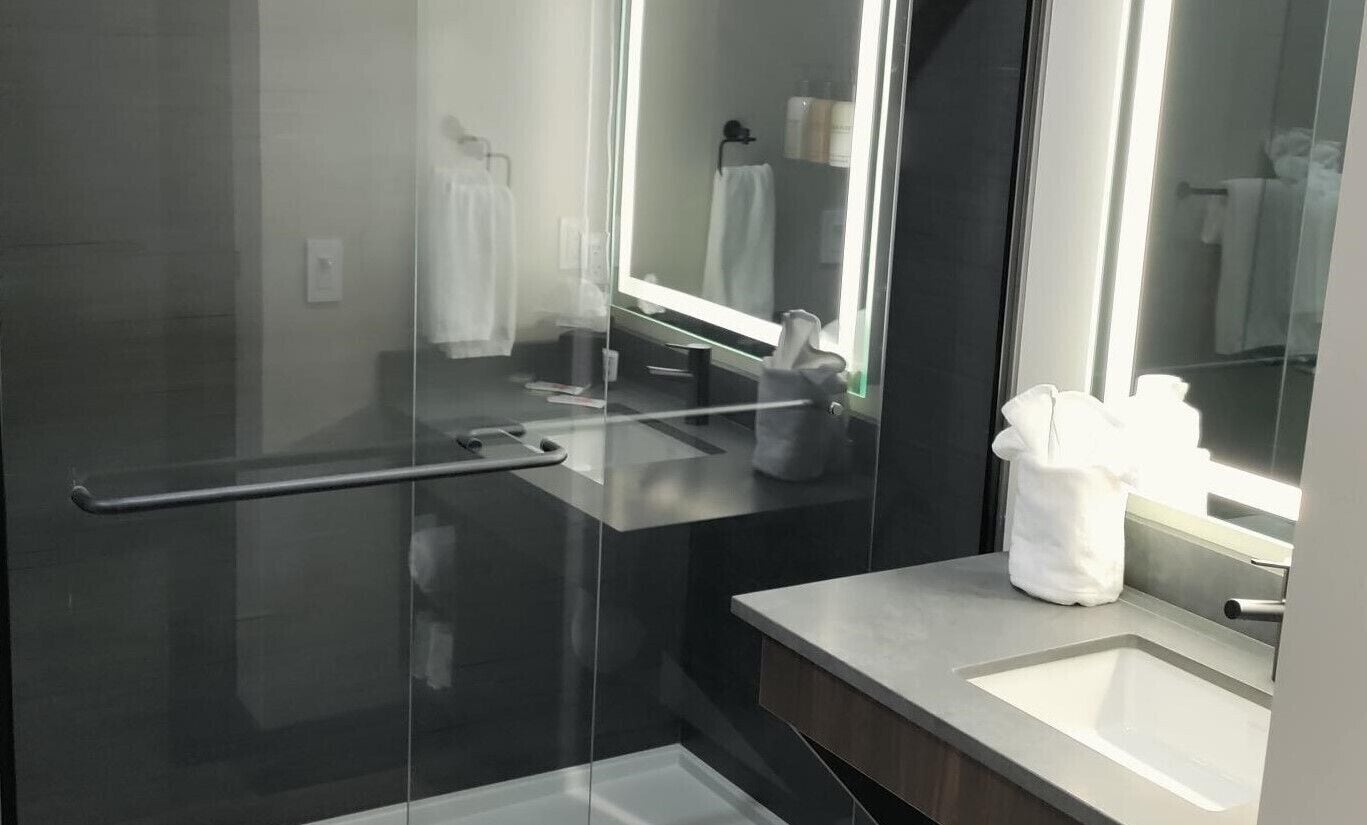 Une salle de bain moderne avec une douche à parois de verre, un meuble-lavabo et un grand miroir.