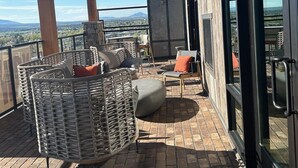 A covered outdoor seating area with wicker furniture and a view of the landscape. - The Bunk House at Cross Keys (Madras)