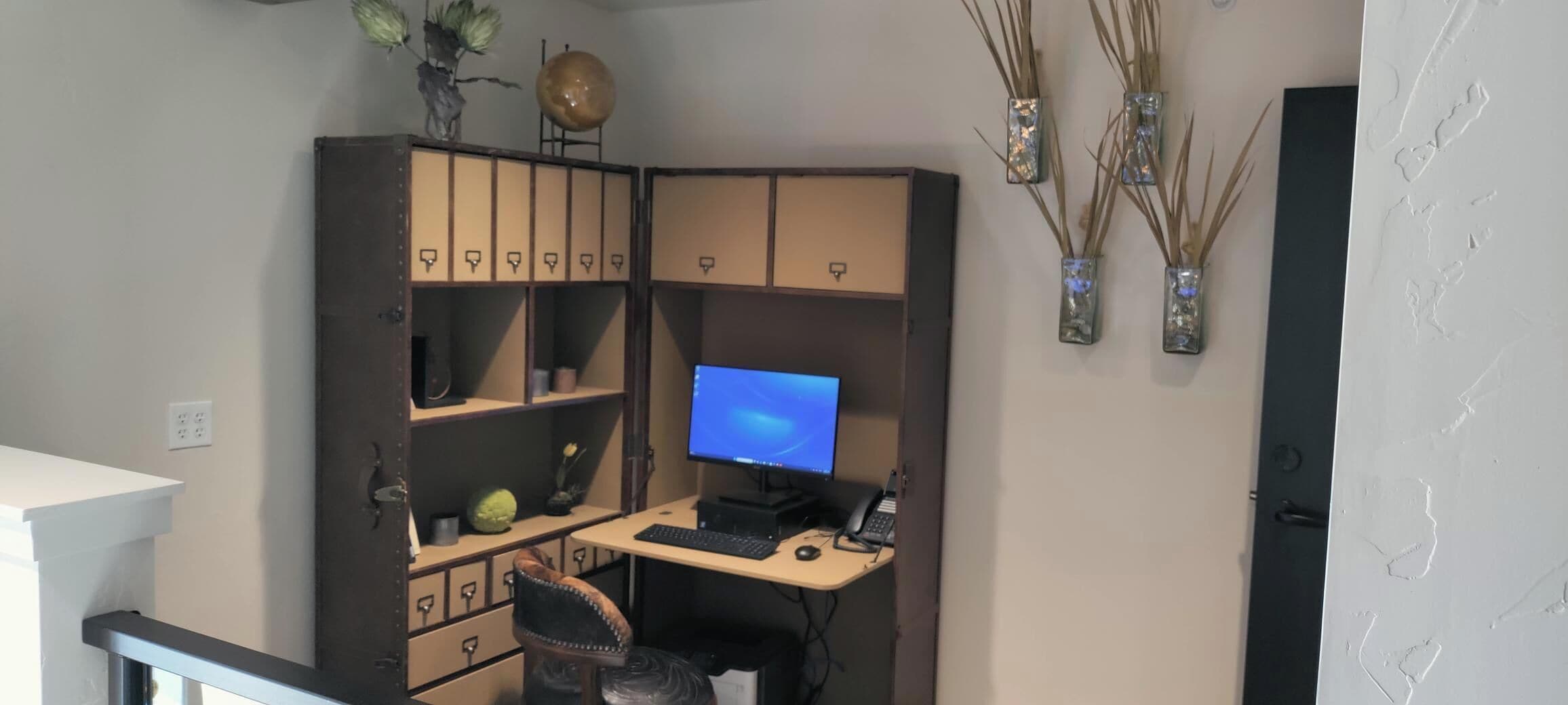 Un espace de travail aménagé à la maison, comprenant un bureau, un ordinateur et des meubles de rangement.