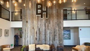 A lobby with a large wooden wall, a brown leather sofa, and hanging light fixtures. - The Bunk House at Cross Keys (Madras)