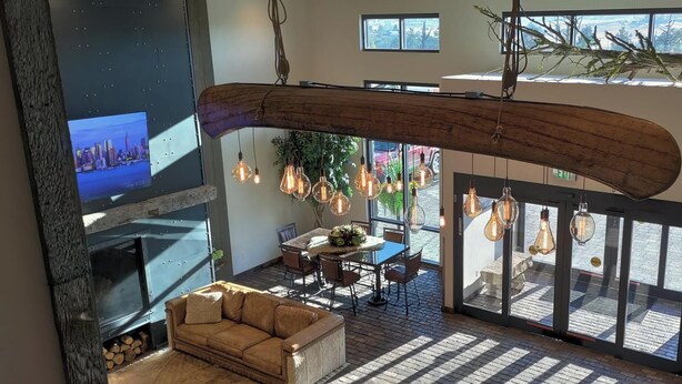 A spacious living area with a fireplace, a dining table, and hanging light fixtures. - The Bunk House at Cross Keys (Madras)