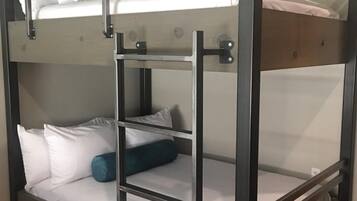 A bunk bed with a ladder, white bedding, and a colorful rug.