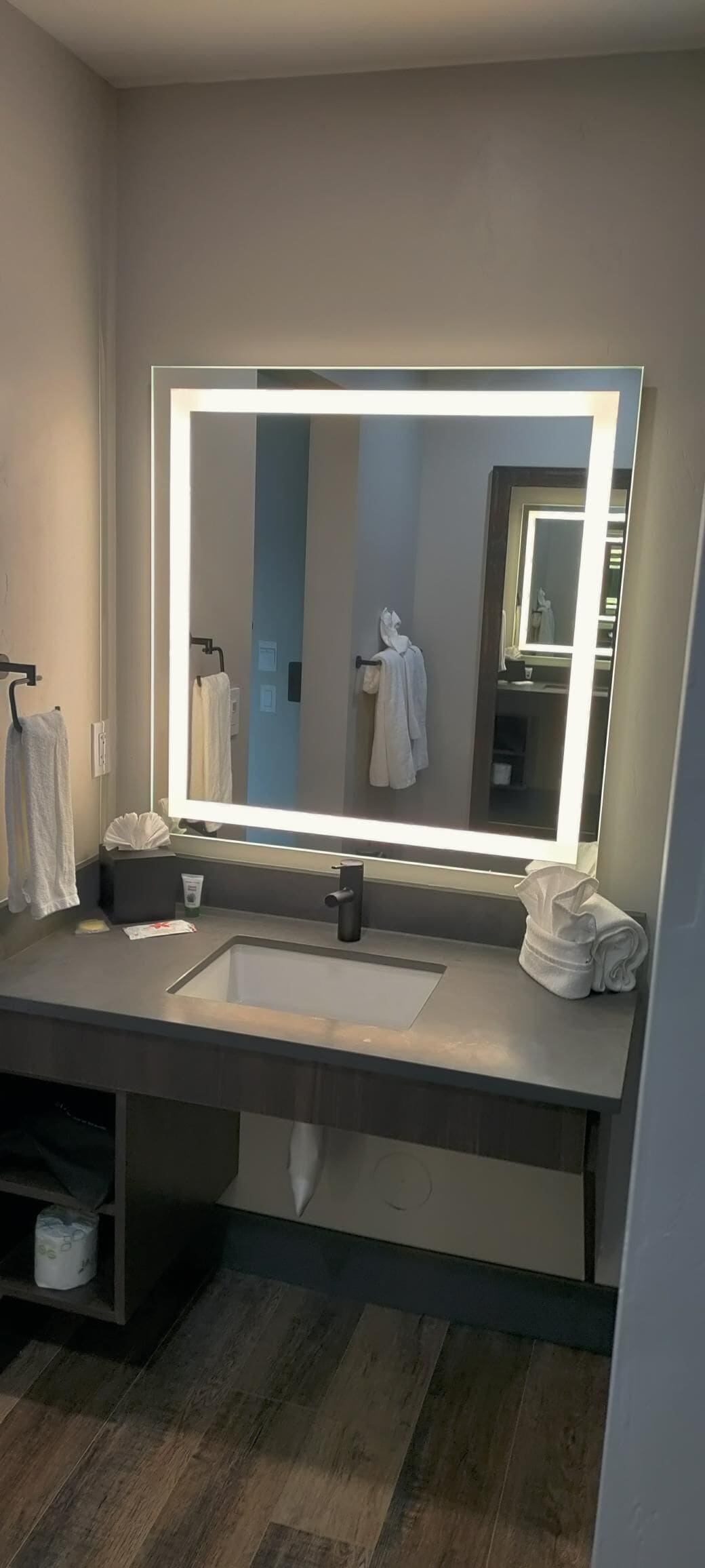 A modern bathroom with a large mirror, a sink, and a towel rack.
