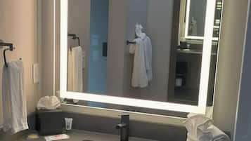 A modern bathroom with a large mirror, a sink, and a towel rack.