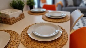 Une table à manger dressée avec des assiettes et des sets de table en fibres tressées, entourée de chaises.