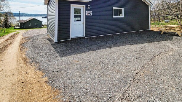 A single-story building with a dark exterior, a white door, and a small window. - Explore and relax with ocean views in Charlottetown Bonavista Bay Newfoundland!  (Charlottetown)