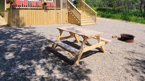 A house with a wooden deck, a covered patio with red chairs, and a gravel driveway. - Explore and relax with ocean views in Charlottetown Bonavista Bay Newfoundland!  (Charlottetown)