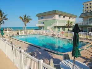 Relax by the oceanfront pool surrounded by lounge chairs and umbrellas.