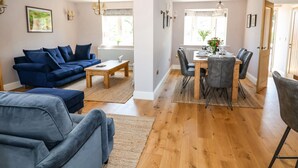 A modern living room with a blue sofa, a wooden coffee table, and a dining area with a table set for four. - Fishermans Lodge (York)