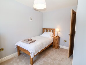 Quarto com cama de madeira, luminária de cabeceira e uma porta à direita.