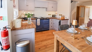Une cuisine moderne avec des meubles blancs, un plan de travail en bois et un coin repas avec une table dressée pour deux personnes.