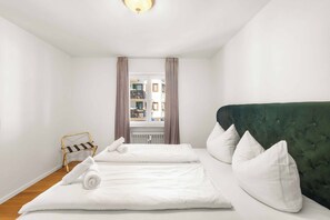 A hotel room with a bed, a green upholstered headboard, white pillows, and a window with curtains. - Königlicher Aufenthalt 10 Minuten zu Fuß zum See (Prien am Chiemsee)