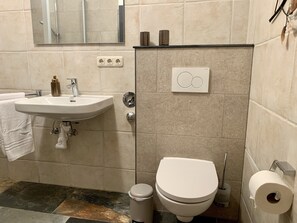 Une salle de bain équipée d’un lavabo, d’un miroir, de toilettes et d’un porte-serviettes.