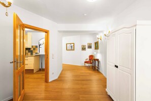 A hallway with wooden flooring, a white door, and a dining area with a red chair and table. - Königlicher Aufenthalt 10 Minuten zu Fuß zum See (Prien am Chiemsee)