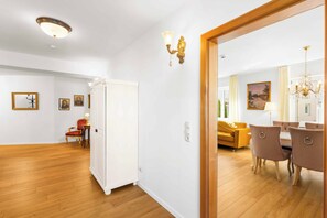 A spacious living area with a wooden floor, a dining table with chairs, a sofa, and a large mirror reflecting the room. - Königlicher Aufenthalt 10 Minuten zu Fuß zum See (Prien am Chiemsee)