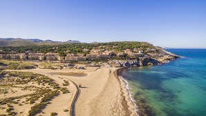 Ein Küstenresort mit Strandvillen, einem Sandstrand und einem Bergpanorama.
