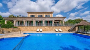 Ein zweigeschossiges Gebäude mit Schwimmbad, Steinmauern und einem Balkon mit weißen Geländern.