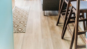 Una sala de estar moderna con un sofá, una silla, una mesa de comedor y una zona de cocina al fondo.